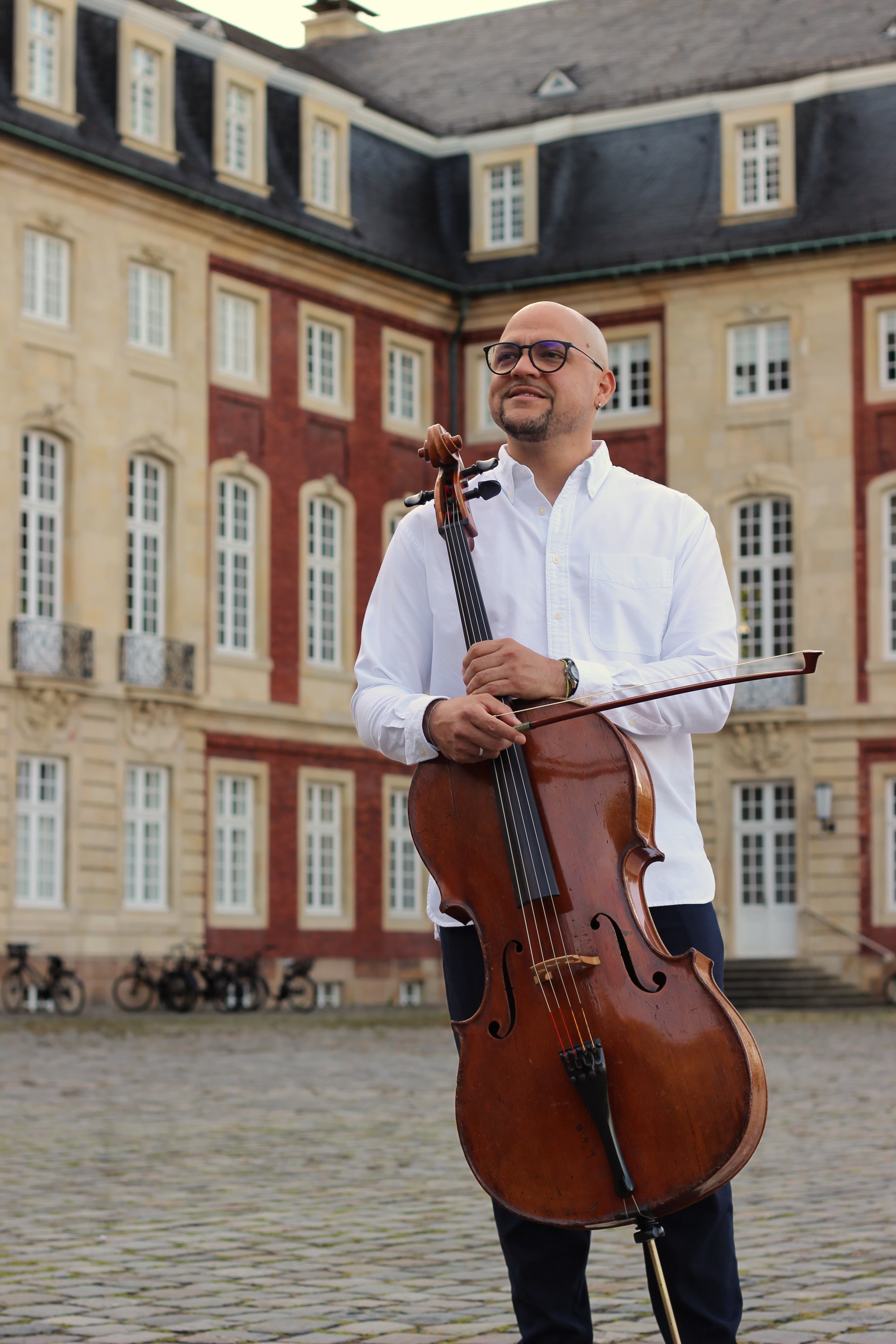 Carlos Ferrer mit seinem Cello vor dem Schloss Münster