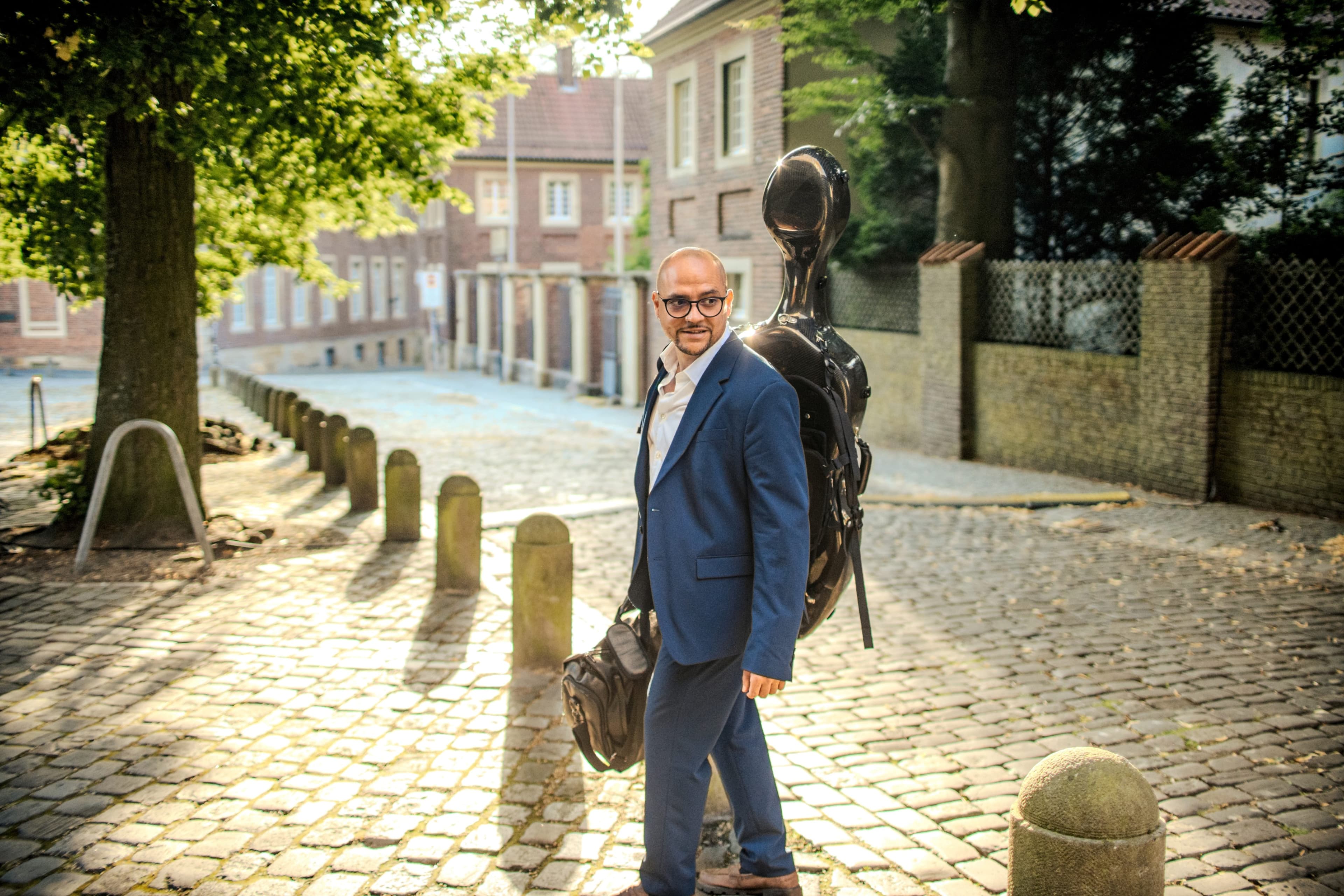 Carlos Ferrer mit Cellokasten auf einer Kopfsteinpflasterstraße in Münster